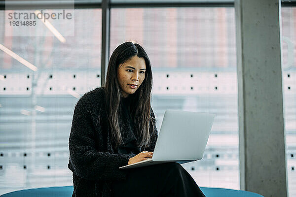 Confident businesswoman using laptop in office