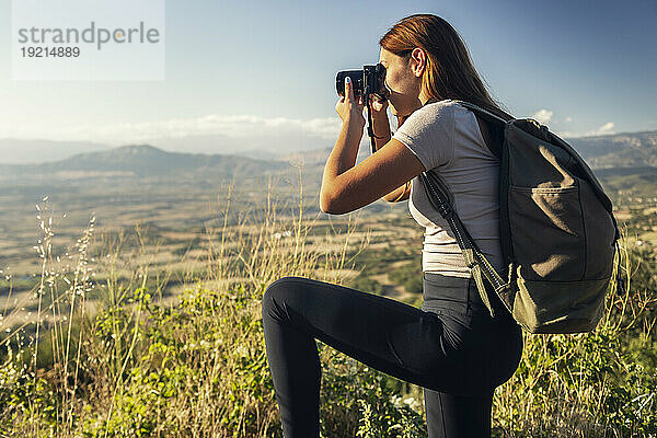 Junger Tourist mit Rucksack fotografiert an sonnigem Tag