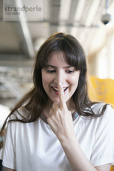 Glückliche Frau berührt Nase mit Finger