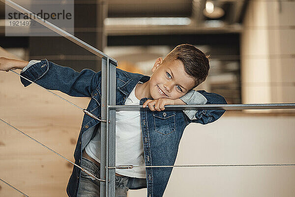 Smiling boy leaning on railing at home