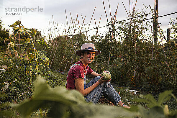 Glückliche Frau hält runde Zucchini im Obstgarten