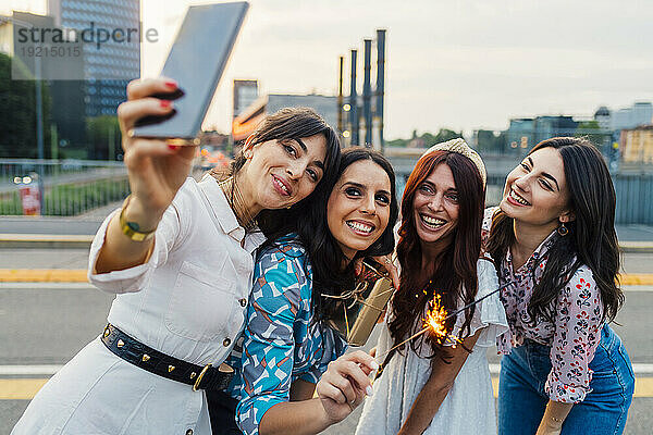 Glückliche Frau  die bei Sonnenuntergang ein Selfie mit Freunden per Handy macht