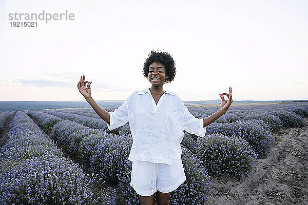 Lächelnde Frau meditiert im Lavendelfeld