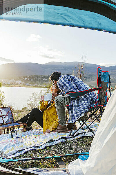 Ein Paar küsst sich und sitzt vor dem Zelt