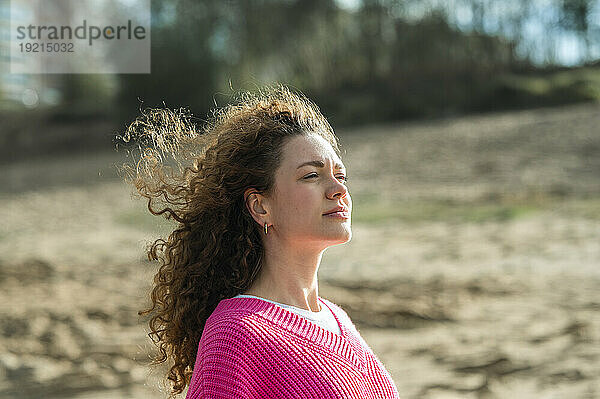 Junge Frau mit lockigem Haar am Strand