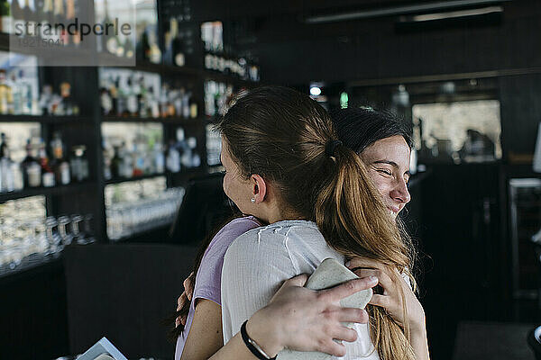 Zwei junge Frauen umarmen sich in der Bar