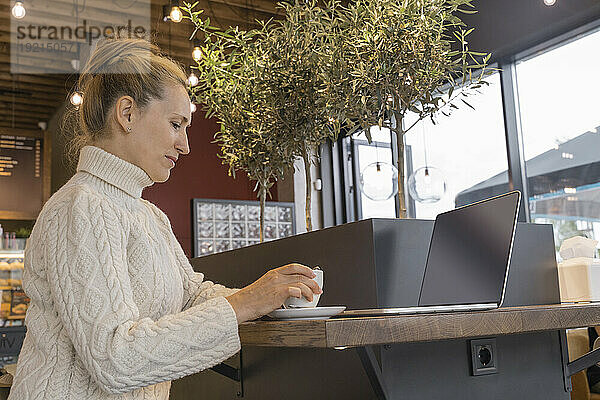 Geschäftsfrau mit Laptop trinkt Kaffee im Café