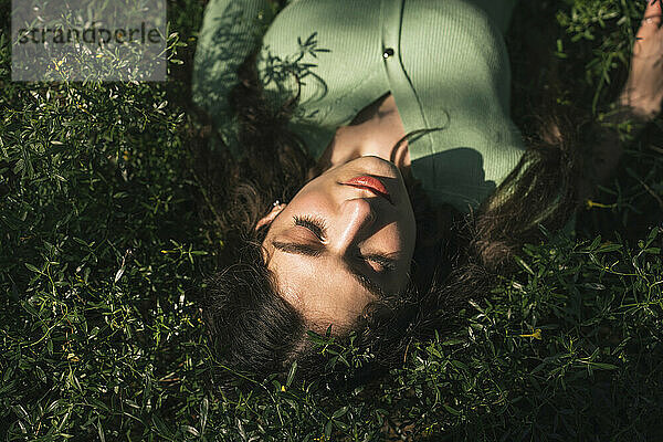Frau mit geschlossenen Augen liegt auf Gras