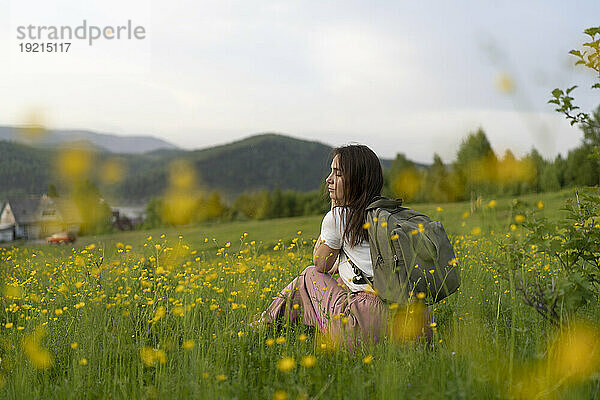 Ruhige Frau mit geschlossenen Augen sitzt im Blumenfeld