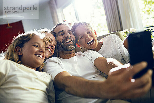 Glücklicher Mann  der zu Hause ein Selfie mit der Familie auf dem Smartphone macht