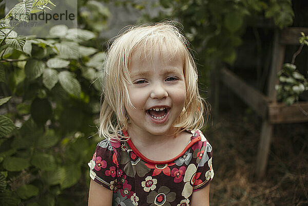 Lächelndes Mädchen in der Nähe von Pflanzen im Garten