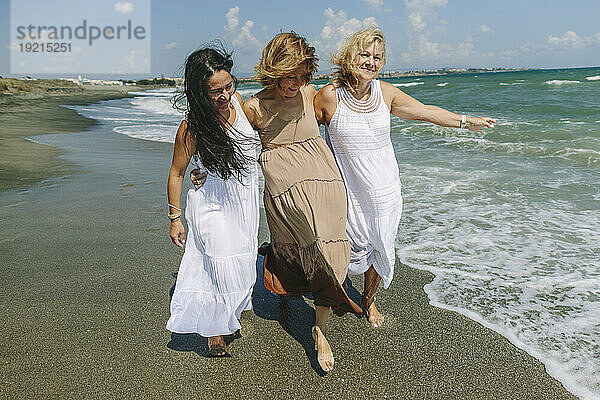 Frauen haben Spaß beim gemeinsamen Spaziergang in Ufernähe am Strand