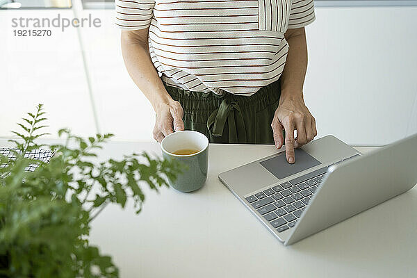 Freiberufler mit Kaffeetasse  der zu Hause am Laptop arbeitet