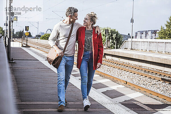 Glücklicher Mann und Frau  die an einem sonnigen Tag gemeinsam am Bahnsteig spazieren
