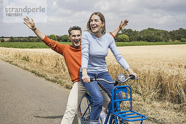 Glücklicher Mann  der Spaß mit einer Frau hat  die in der Nähe des Feldes Fahrrad fährt