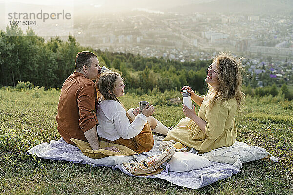 Glückliche Familie beim Tee auf der Picknickdecke auf der Wiese