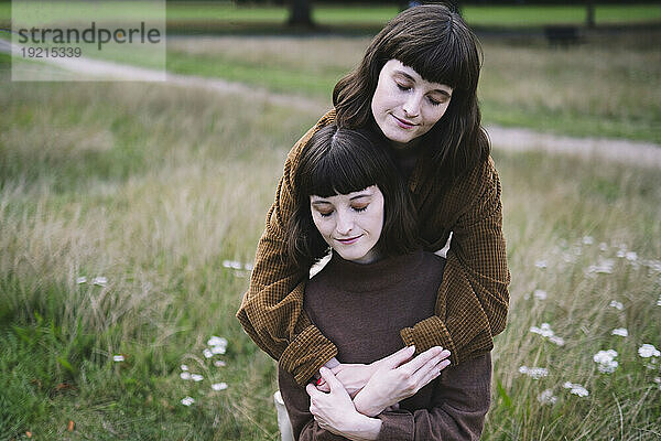 Liebevolle Zwillingsschwestern umarmen sich im Park