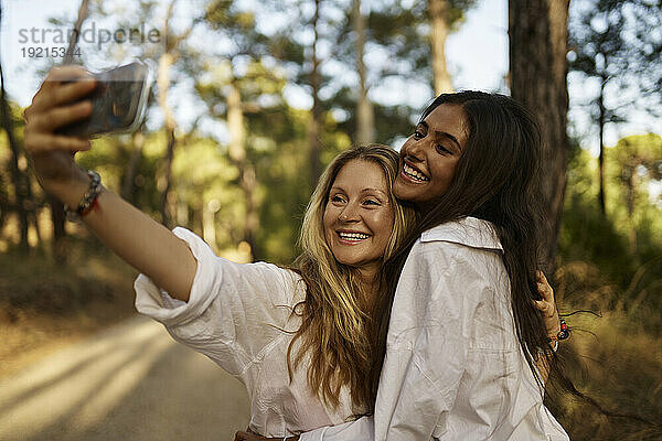 Glückliche Frau macht Selfie mit Teenager-Tochter im Wald