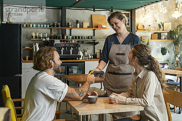 Kunden  die mit Kreditkarte bezahlen  sitzen im Café