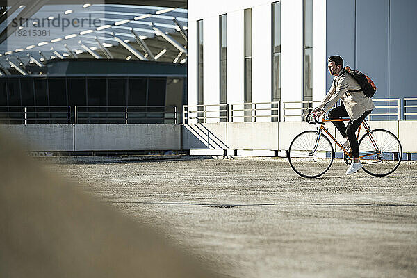 Mann fährt an sonnigem Tag Fahrrad auf Parkplatz