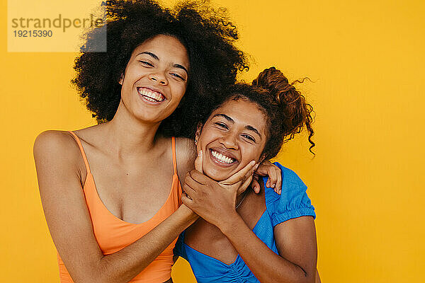 Fröhliche  gemischtrassige Freunde  die vor gelbem Hintergrund lachen