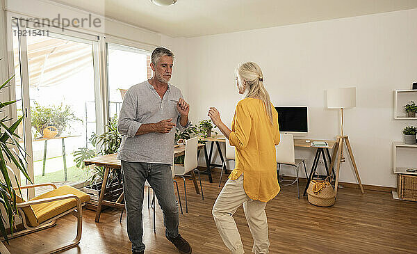 Sorgloses Paar tanzt zu Hause gemeinsam im Wohnzimmer