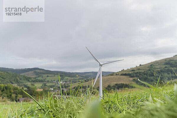 Windturbinenmodell auf Gras unter bewölktem Himmel auf der Wiese