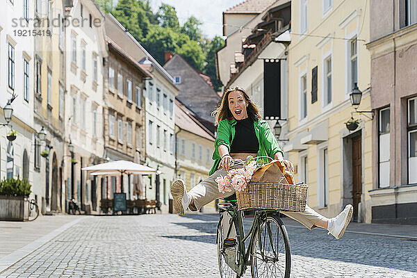 Fröhliche Frau fährt Fahrrad auf der Straße in der Stadt