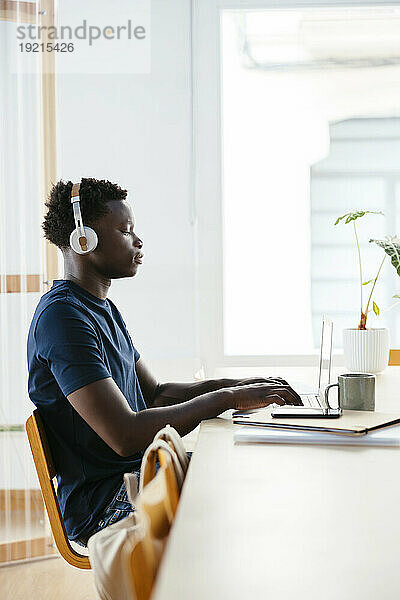 Student mit kabellosen Kopfhörern studiert an der Universität am Laptop