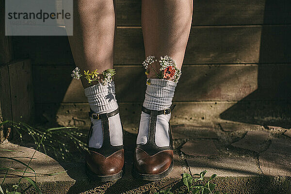 Frau trägt Vintage-Schuhe mit Wildblumen in weißen Socken