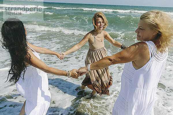 Glückliche Frauen  die am Strand zusammen am Meer spielen