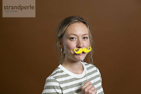 Blonde Frau mit Schnurrbart-Requisite im Studio