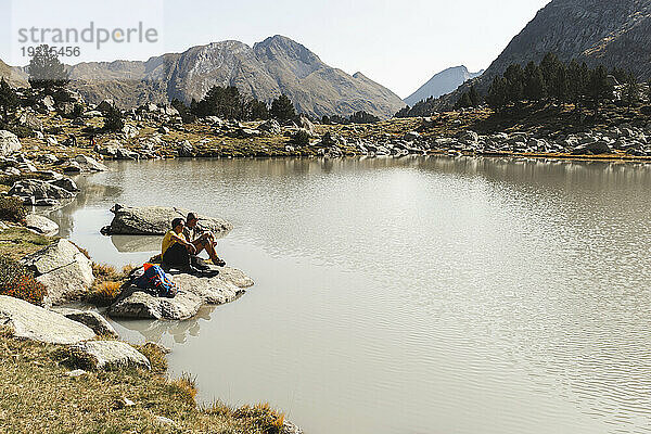Freunde sitzen auf einem Felsen in der Nähe des Sees