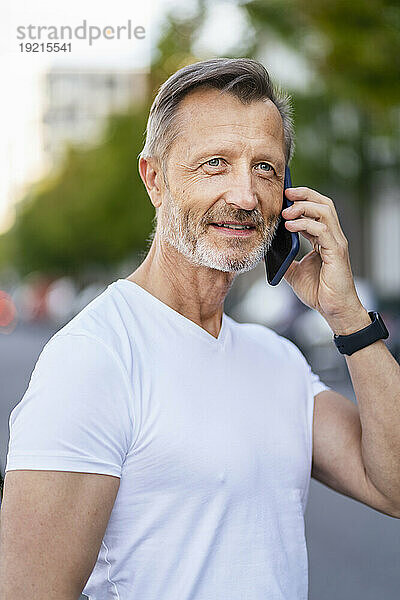 Lächelnder Mann  der über sein Smartphone spricht