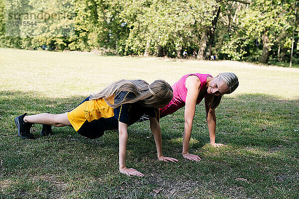 Glückliche Mutter und Tochter trainieren im Park