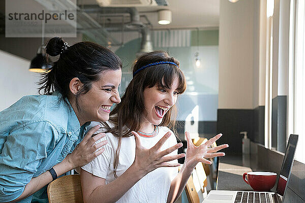 Aufgeregte Frauen schauen im Café auf Laptop
