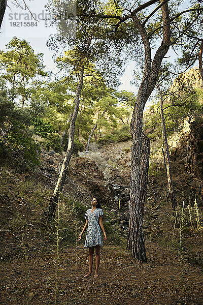 Teenager-Mädchen steht neben Bäumen im Wald