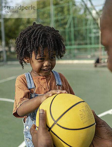 Vater gibt verspieltem Sohn Basketball auf dem Sportplatz