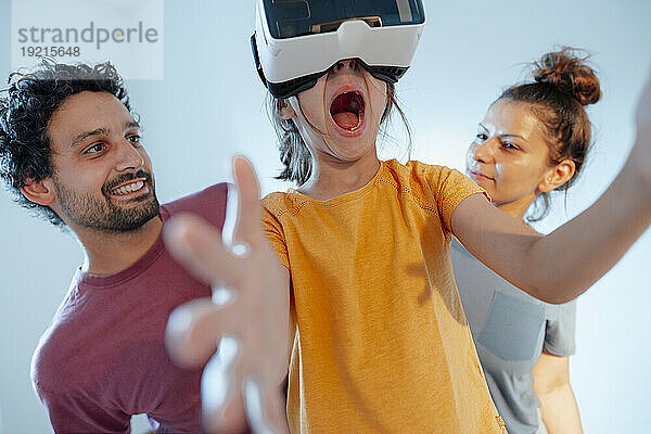 Glücklicher Mann und Frau mit Tochter  die zu Hause Virtual-Reality-Simulatoren tragen