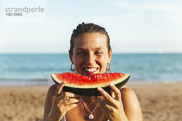 Glückliche Frau genießt Wassermelone am Strand