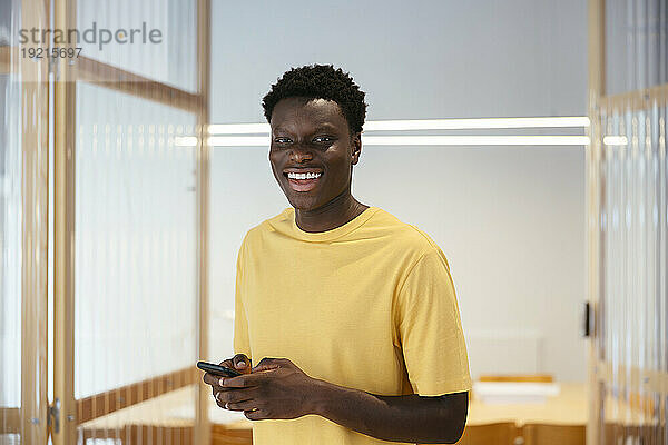 Lächelnder Student steht mit Smartphone
