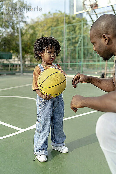 Vater spricht mit Sohn und erklärt es auf dem Basketballplatz