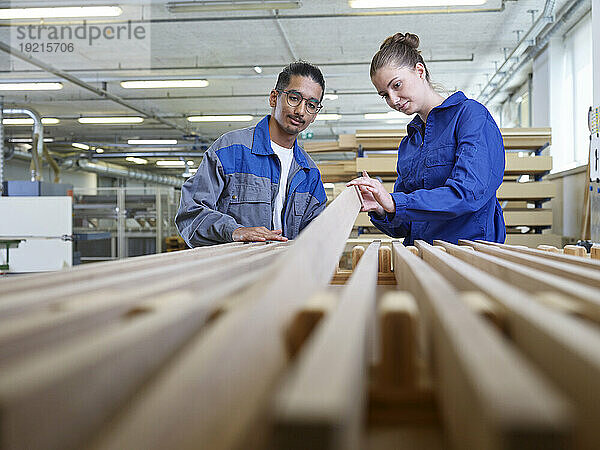 Trainees examining wooden plank in workshop