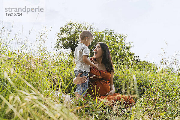 Pregnant mother enjoying with son in meadow