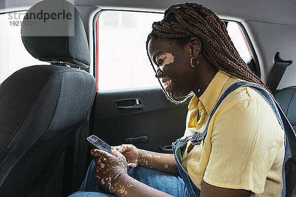 Lächelnde Frau benutzt Smartphone im Auto