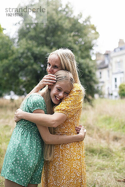 Lächelndes Mädchen umarmt Mutter im öffentlichen Park