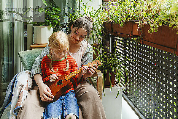 Teenage girl teaching sister how to play ukulele