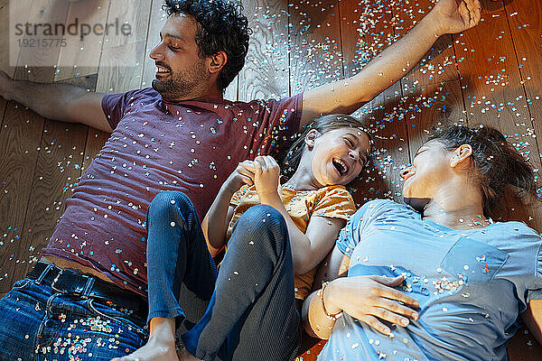 Happy family lying on floor with confetti at home