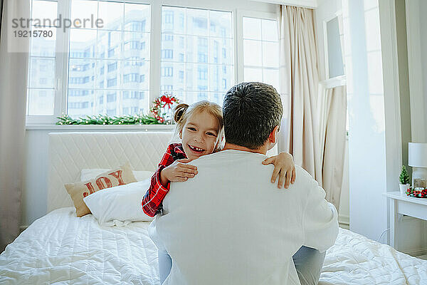 Glückliche Tochter umarmt Vater zu Hause im Bett