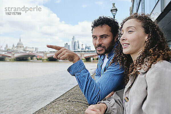 Man gesturing with woman standing near wall in city